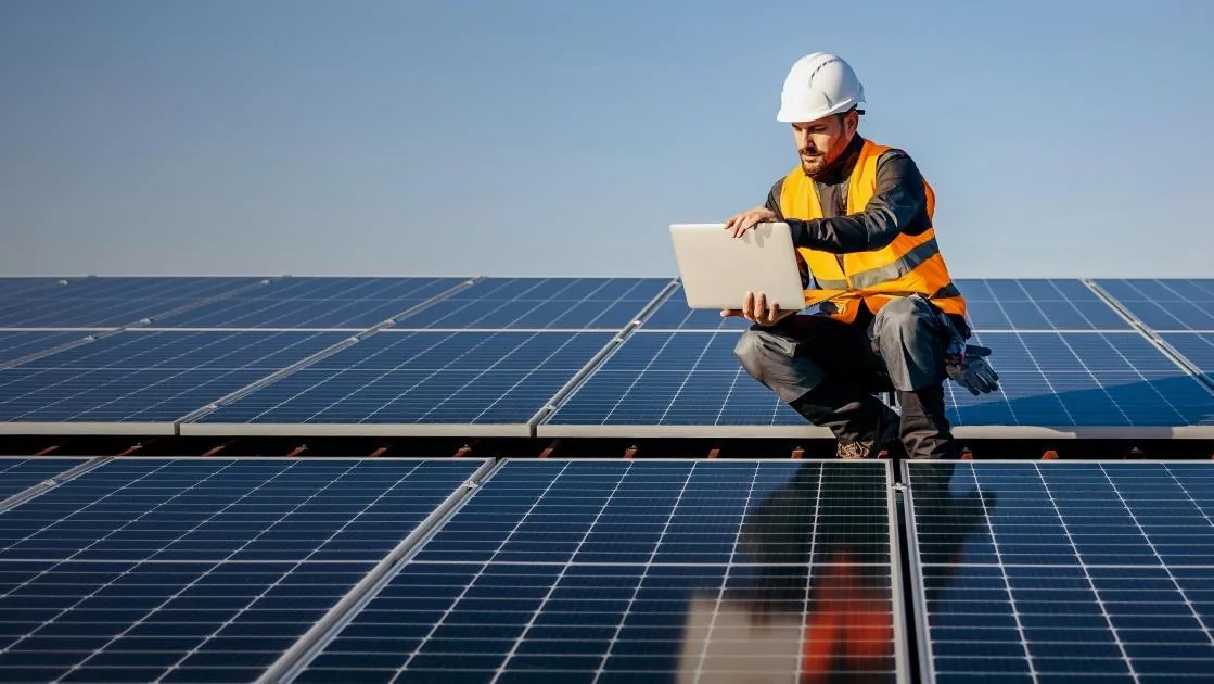 Techniker konfiguriert am Laptop das Energiemanagement einer Photovoltaikanlage auf dem Dach